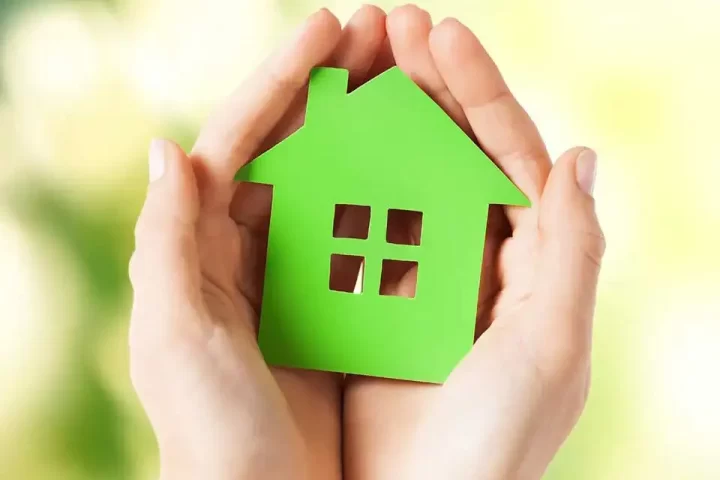 hands holding a green house figure
